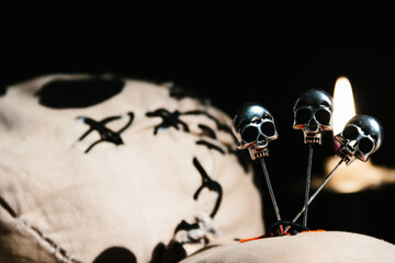 Close up Voodoo magic ritual doll laying on a wooden table on a black background with candles 