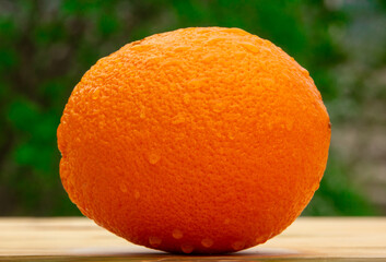 Close up of a fresh bright tasty orange on a wooden table in the garden, natural vegan food
