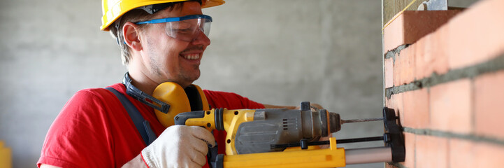 Builder drilling hole in wall, construction site