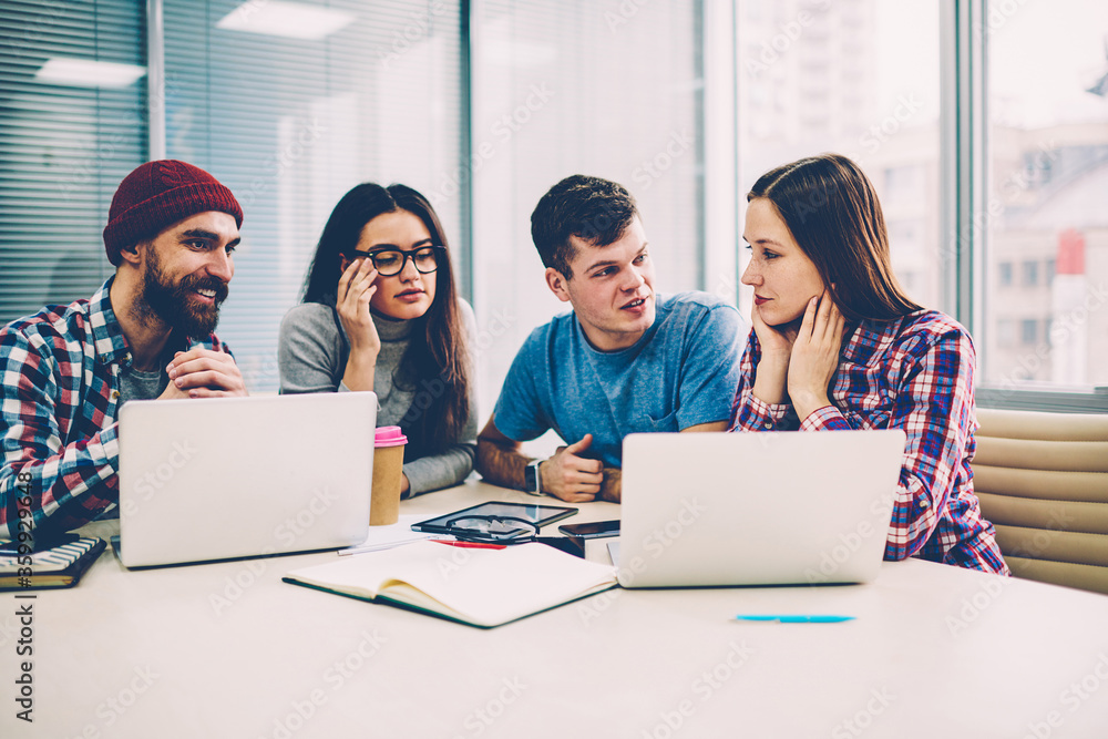 Poster group of skilled professional freelancers working together indoors using laptops and good connection