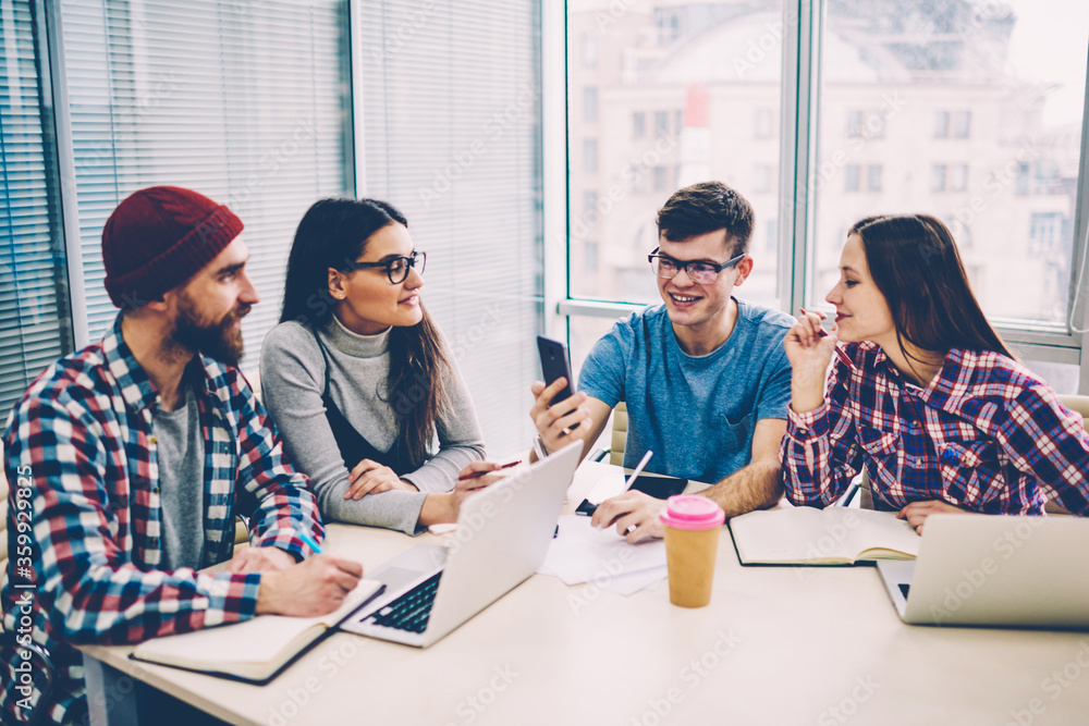 Poster successful smiling hipster guy making video call via smartphone with 4g connection while sitting wit