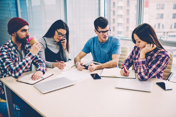 Team of casual dressed young people together with professional leader discussing working plans and schedule having briefing meeting in office.Group of creative students collaborating on common task