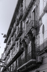 Old building with bars on the balconies sunset and trees around it in black and white
