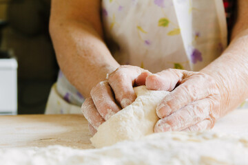 Obraz na płótnie Canvas Cooking at home, old woman's hands kneading dough