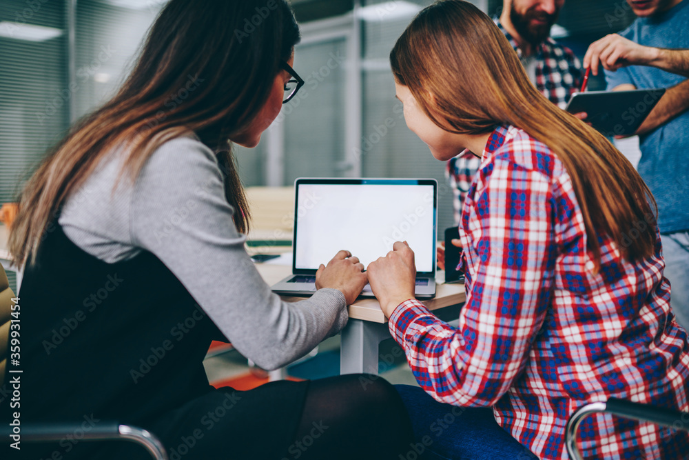 Poster two hipsters girls typing text message to friend using laptop computer with mockup screen, female co