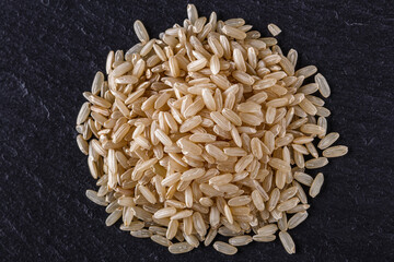 raw brown rice on a dark stone background