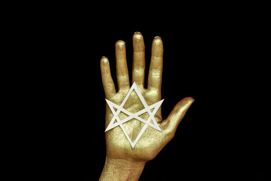 Golden hand on black background with six pointed star Unicursal hexagram.