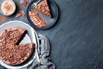 Chocolate cake piece with chocolate and fruits on black rustic table