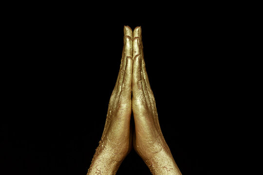 Two golden hands raised up, pray, black background