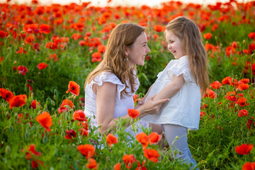 Naklejka na ściany i meble Beautiful mother and her daughter in spring poppy flower field, Czech republic