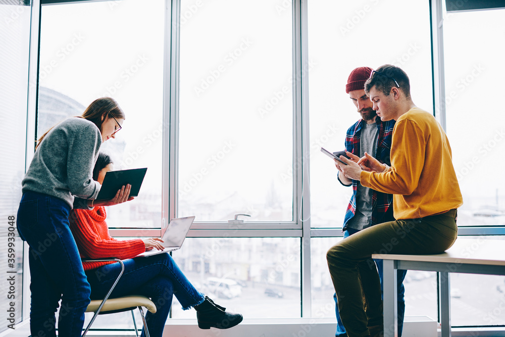 Aufkleber busy young people dressed in casual wear collaborating with each other using modern devices and inte