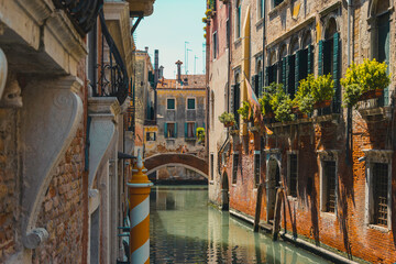 Typical ancient canal in venice, italy, during sunset, with striped pole for gondolas