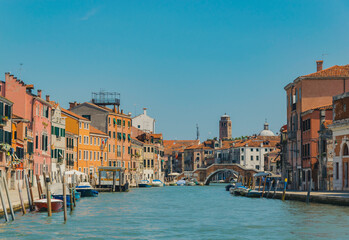 View of a canal in Venice, Italy, with boats, docks, ancient buildings and clear sky