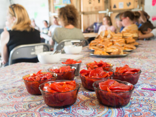 table with red food in bowls people backwards