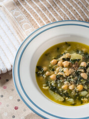chickpeas spinach and cod on white plate with blue border next kitchen cloth