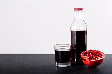 Pomegranate juice and red pomegranate fruit on the table. Copy space.