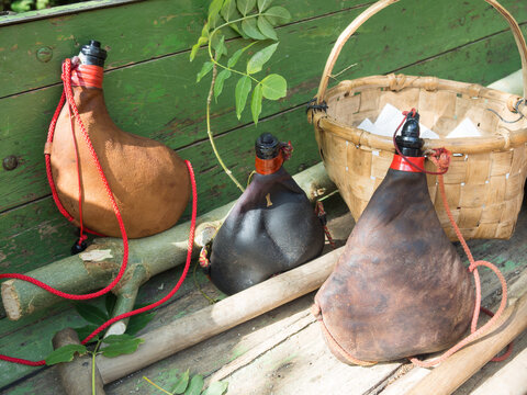 rural scene with three wineskin traditional spanish wine container on a green wood suface next to wicker basket