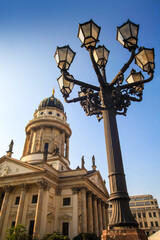 Fototapeta na wymiar View of the old street dark lamp and the French cathedral on Gendarmenmarkt square in Berlin, Germany. Sunny day.