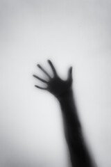 Concept of a frightened woman behind sheet with backlighting in monochrome