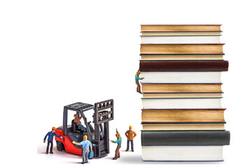 miniature worker driving forklift truck with stack vintage aged book isolated on white...