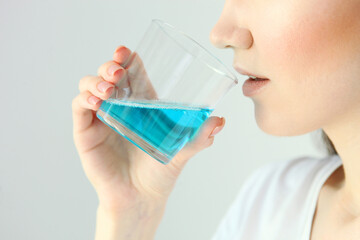 young girl uses mouthwash at home
