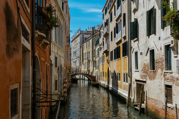 Fototapeta na wymiar Typical canal in Venice, italy, between ancient buildings with bridge in the distance