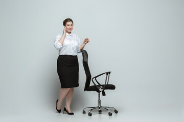 Confident. Young woman in office attire. Bodypositive female character, feminism, loving herself, beauty concept. Plus size businesswoman on gray background. Boss, beautiful. Inclusion, diversity.