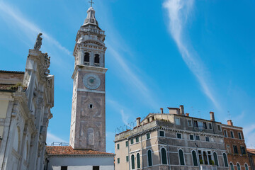 Bell tower of an ancient church in Venice and ancient buildings, with clear sky in the background