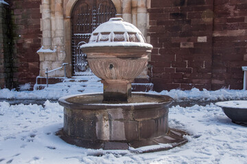 Postcard of the medieval town of Prades (in Catalonia, Spain) full of snow, with the church of Santa María and its typical fountain