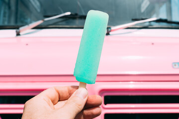 Pastel blue ice cream with a pink ice cream truck or van in the background. High quality photo. POV shot. Point of view.