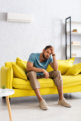 Selective focus of man suffering from heat on couch at home