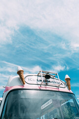 Ice cream cone with a pink retro ice cream truck or van in the background. High quality photo....