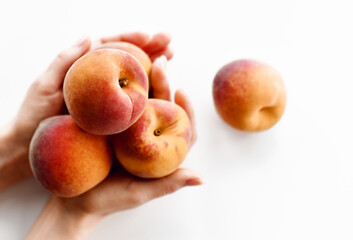 Woman hands holds full palms of fresh sweet peaches on white background. Organic superfood concept for healthy eating 