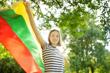 Cute young girl holding tricolor Lithuanian flag on Lithuanian Statehood Day.
