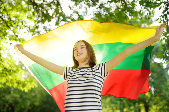 Cute young girl holding tricolor Lithuanian flag on Lithuanian Statehood Day.
