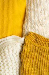 Pile of knitted clothes yellow white color. Autumn winter concept. Copy Space