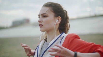 Young sporty woman in headphones performs stretching and warming before running