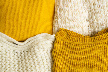 Pile of knitted clothes yellow white color. Autumn winter concept. Copy Space