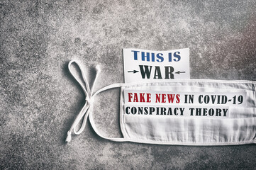 
This is war. Fake news in Covid-19. Conspiracy theory. Textured concrete background. Reusable mask.