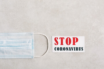 Stop coronavirus. Red-black inscription on a light beige background. Disposable surgical mask. Social distance, Quarantine. Copy space for text.