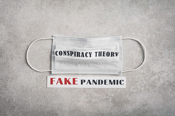 Fake pandemic. Conspiracy theory. The inscription on a light gray background and a medical mask....