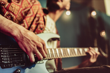 Close up of male hand playing electric guitar in the dark