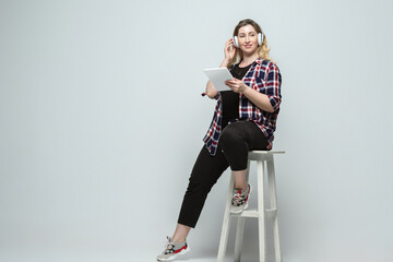 Devices, gadgets. Young woman in casual wear on gray background. Bodypositive character, feminism,...