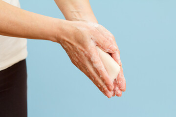 Fototapeta premium Woman washing hands with soap on blue background.