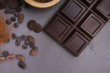 Chocolate bar and drops on the grey table