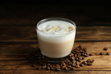 Delicious latte macchiato and coffee beans on wooden table