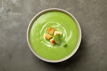 Tasty homemade zucchini cream soup on grey table, top view