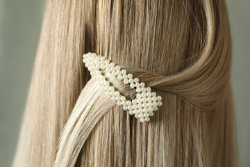 Young woman with beautiful hair clip on grey background, closeup