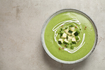 Tasty homemade zucchini cream soup on light table, top view. Space for text