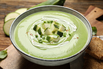 Tasty homemade zucchini cream soup in bowl, closeup